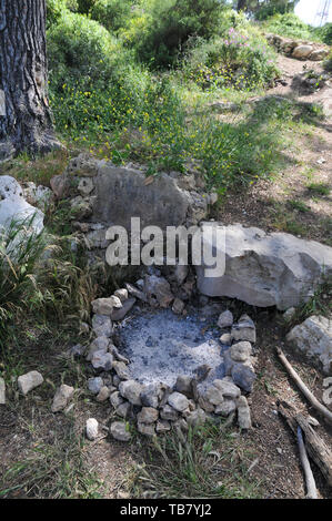 burnt out campfire in a fire pit. stones in a circle around the fire is to prevent the fire from spreading Stock Photo