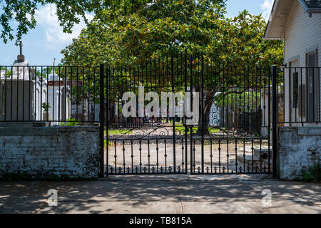 New Orleans, LA, USA -- May 26, 2019.  Landscape photo looking through a gate to St Louis Cemetery #3; tourists in the distance are on a tour of the g Stock Photo