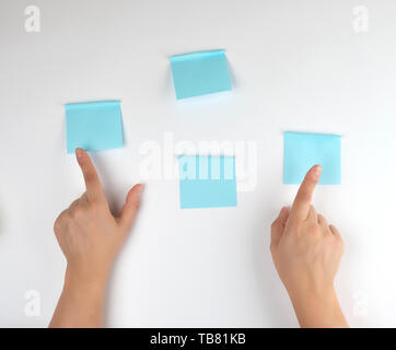 lot of blue stickers on a white background and two female hands pointing at them, conceptual background Stock Photo