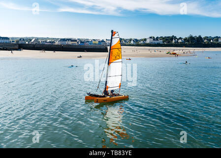 Morgat, France - August 4, 2018:  Catamaran sailing in the port of Morgat against the beach and the townscape. Sunny day of summer Stock Photo