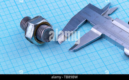 bolt with nut and caliper on engineering paper Stock Photo