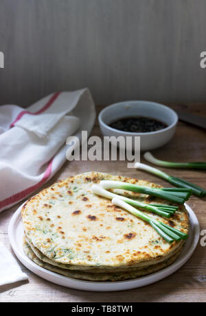 Homemade appetizing scallion pancakes and a bunch of green onions. Rustic style. Stock Photo