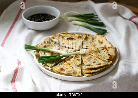 Homemade appetizing scallion pancakes and a bunch of green onions. Rustic style. Stock Photo