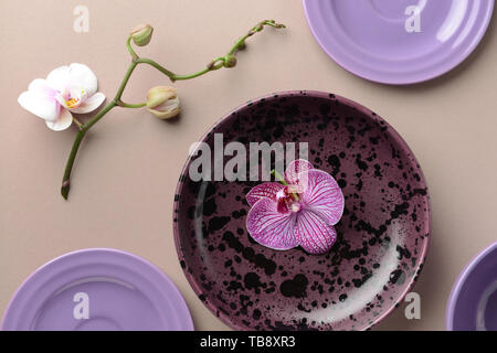 Composition with plates and orchid flowers on table Stock Photo
