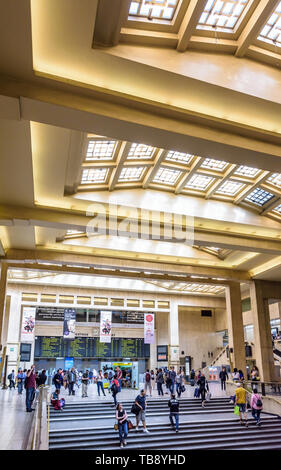 Passengers waiting or walking up and down the stairs under the glass roof in the concourse of Brussels central station. Stock Photo