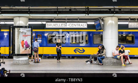 Passengers waiting on a platform in Brussels central station while a train from the dutch railway company Nederlandse Spoorwegen is stationing. Stock Photo