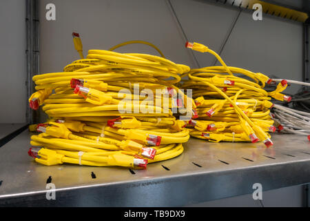 Bright Yellow Ethernet Cables Coiled and Stacked in Storage Rack Server Room Stock Photo