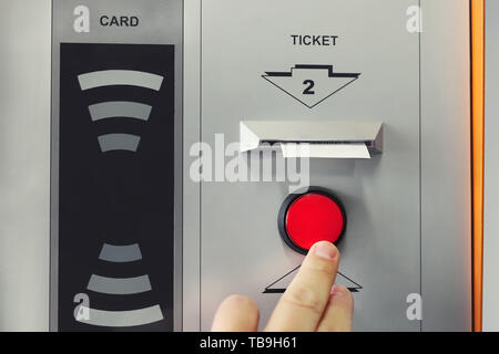 Man hand pushing red button to recieve ticket at car parking entrance. Ticket printing terminal machine with wireless card access technology. Stock Photo
