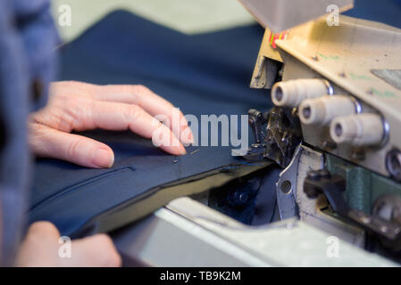 Seamstress sews clothes on a sewing machine. Textile factory . Stock Photo