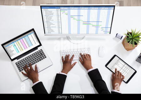 An Overhead View Of Businessperson Doing Multitasking Work At Workplace Stock Photo