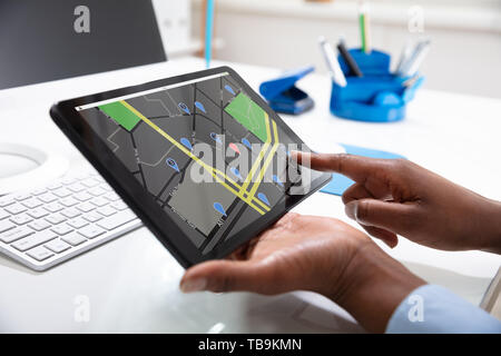 Close-up Of A Woman's Hand Using GPS Navigation Map On Digital Tablet Over The Desk Stock Photo