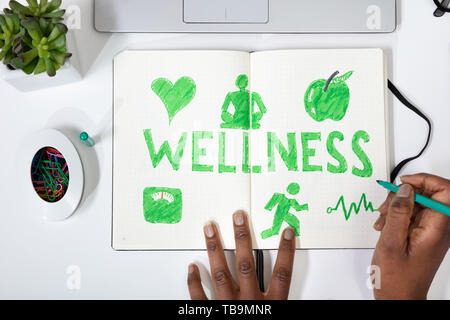 High Angle View Of A Human Hand Drawing Wellness Concept On Notebook Stock Photo