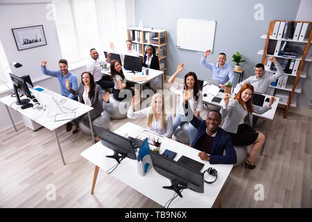 High Angle View Of Happy Multi-ethnic Businesspeople Waving Hands In Office Sitting On Fitness Ball Stock Photo