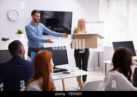 Smiling Young Manager Welcoming New Female Employee Introducing Her To Old Colleagues At Workplace Stock Photo