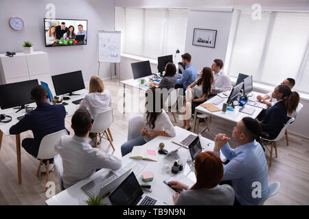 Rear View Of A Business People Looking At Screen During Video Conference In Office Stock Photo
