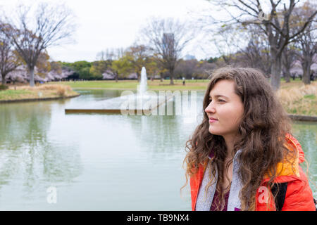 Tokyo, Japan Yoyogi park with young happy tired tourist woman standing looking at lake pond in downtown on cloudy day Stock Photo