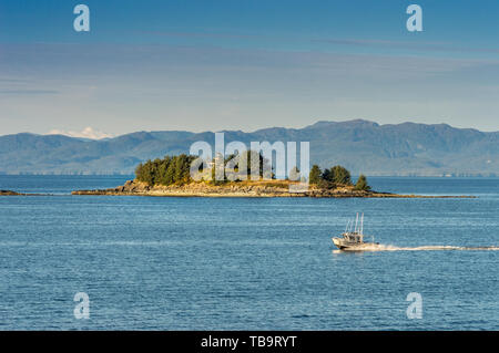 September 17, 2018 - Tongass Narrows, AK: Small aluminum hull fishing boat passing by Guard Islands and old lighthouse, early morning, near Ketchikan. Stock Photo