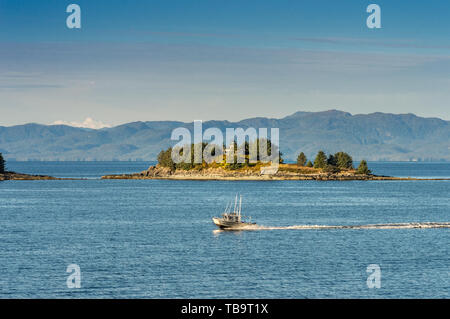 September 17, 2018 - Tongass Narrows, AK: Small aluminum hull fishing boat passing by Guard Islands and old lighthouse, early morning, near Ketchikan. Stock Photo