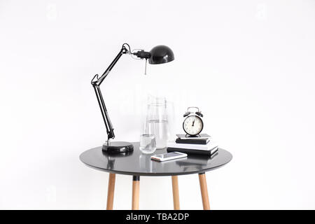 Books, alarm clock and lamp on table against white background Stock Photo