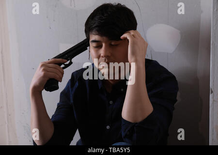 Young man with gun going to commit suicide at home Stock Photo