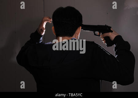 Young man with gun going to commit suicide at home Stock Photo