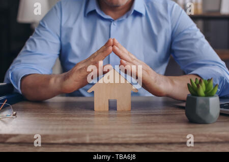 Male insurance agent with figure of house at table, closeup Stock Photo