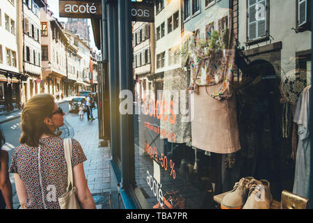 Strasbourg, France - Jul 22, 2017: Rear view of beautiful young woman in French city admiring current sales soldes offers in clothes fashion store Stock Photo