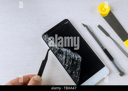 Broken phones on cracked screen details of the cell phone repair tools Stock Photo