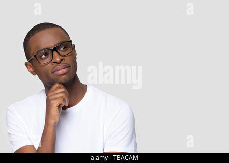 Pensive thoughtful young guy pose on grey wall looking aside Stock Photo