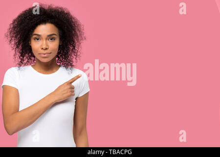 Serious confident african woman looking at camera pointing finger aside Stock Photo