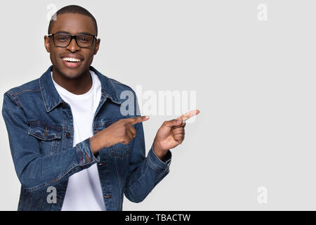 Smiling african man wearing glasses looking at camera pointing aside Stock Photo