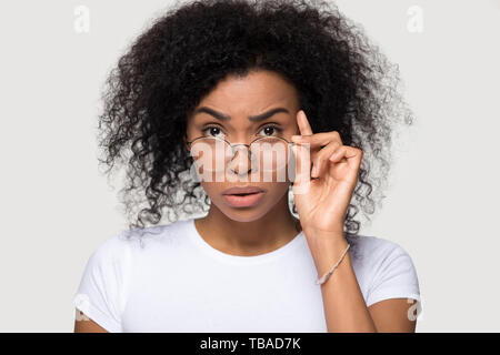 Shocked african young woman lowering glasses looking at camera Stock Photo