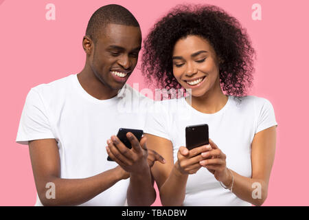 Attractive african couple holding smart phones smiling having fun Stock Photo