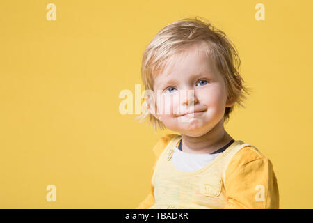 Young Blonde Girl in Yellow Dress Cheerfully Laughing, Smiling and Having Fun on Yellow Background Stock Photo