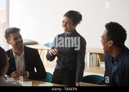 Multiracial diverse employee laugh talking discussing ideas at meeting Stock Photo
