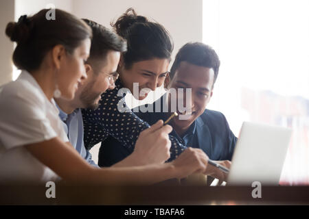 Smiling diverse colleagues laugh brainstorming using laptop Stock Photo