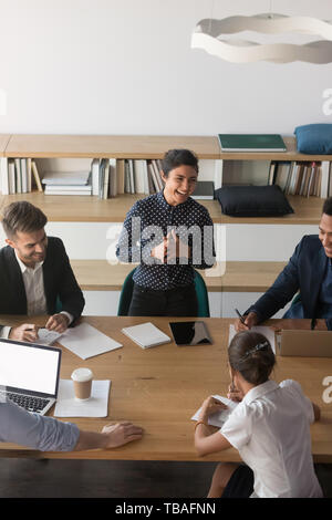 Multiethnic employees laugh discussing ideas at meeting Stock Photo
