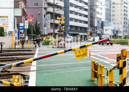 Tokyo, Japan - March 30, 2019: Shinjuku or Shibuya street sidewalk road by buildings during day with railroad crossing and closed gate sign translatio Stock Photo