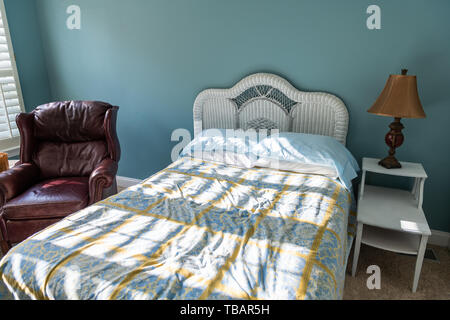 New clean bed with table and lamp vintage beach theme blue green pillows in bedroom in house or apartment by red leather couch Stock Photo