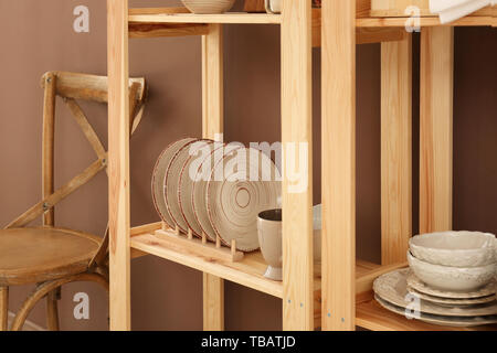 Set of clean dishes on wooden shelves near color wall Stock Photo