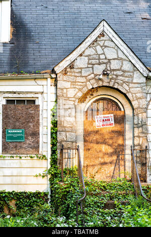 Atlanta, USA - April 21, 2018: Old abandoned wooden house with entrance and notice sign warning and company buying for cash and number Stock Photo