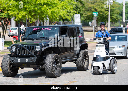 Montgomery, USA - April 21, 2018: Alabama city police officer car scooter on street and Jeep with sign for Fit Chic Stock Photo