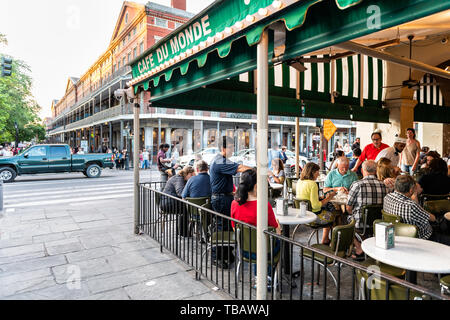 New Orleans, USA - April 22, 2018: People sitting at tables at iconic Cafe Du Monde restaurant famous for beignet powdered sugar donuts and chicory co