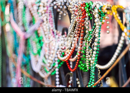 New Orleans, USA closeup of multicolored mardi gras beads hanging on fence by colorful building house and nobody on sidewalk Stock Photo