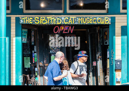 New Orleans, USA - April 23, 2018: Frenchmen street in Louisiana old building entrance sign to famous Spotted Cat Music Club and people walking during Stock Photo