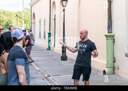 New Orleans, USA - April 23, 2018: Old town street in Louisiana city with many people walking on sidewalk by building wall tour group Stock Photo