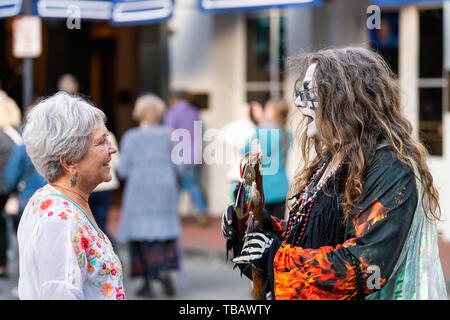 New Orleans, USA - April 23, 2018: Downtown old Bourbon street in Louisiana famous city with people woman talking to person in costume Stock Photo