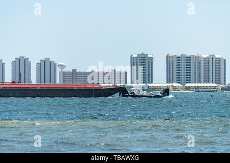 Navarre, USA - April 24, 2018: Towboat or tugboat towing tank barge boat ship vessel in Pensacola bay near sea ocean shore of Gulf of Mexico, Florida  Stock Photo
