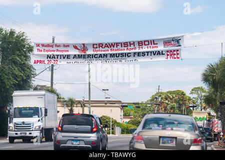 Fort Walton Beach, USA - April 24, 2018: Road sign banner for Native American Music Festival and seafood restaurant hanging above road street with car Stock Photo