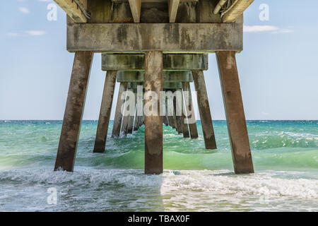 Under Okaloosa fishing pier in Fort Walton Beach, Florida with pillars, green shallow waves in Panhandle, Gulf of Mexico on summer sunny day Stock Photo